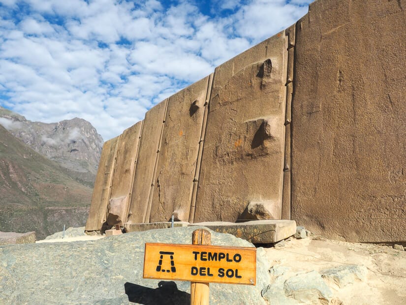 A sign that says "Templo del Sol" in front of huge pink stones of the Sun Temple at Ollantaytambo ruins