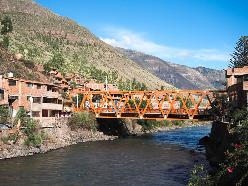 An orange metal bridge across the river in Pisac