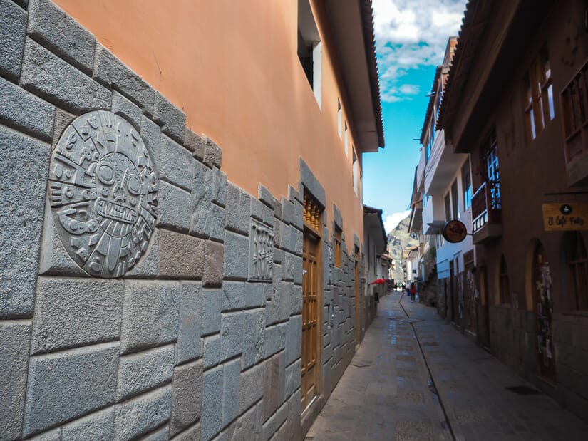 A narrow street in Pisac with a stone Inca symbol and stonework