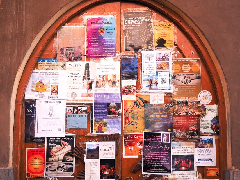 A wall covered in posters advertising yoga, massage, meditation, healing ceremonies, and so on in Pisac