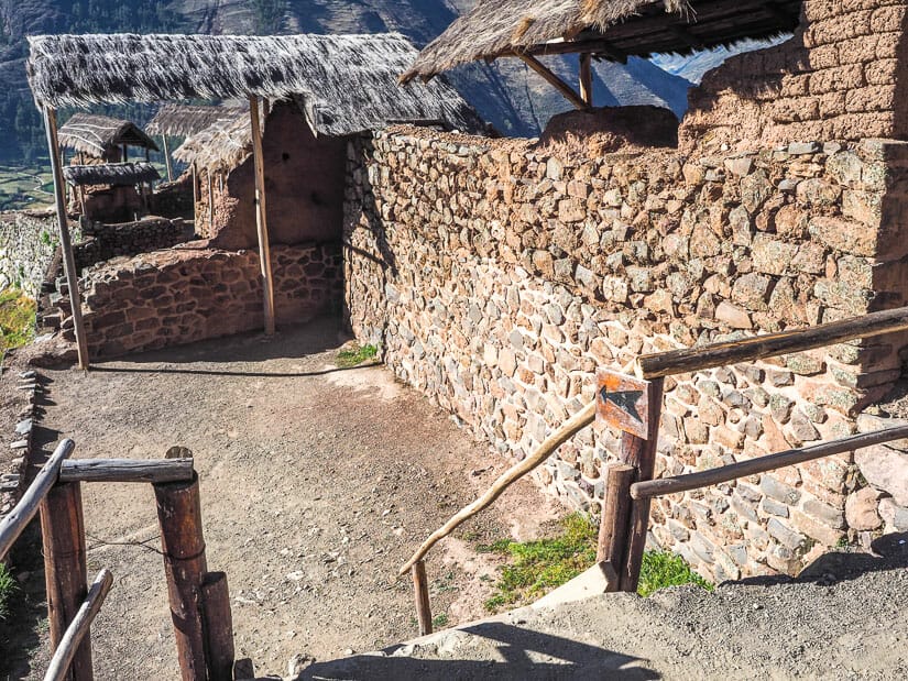 A small staircase leading down to some ruins at Pisac, with a small sign with an arrow pointing down the stairs