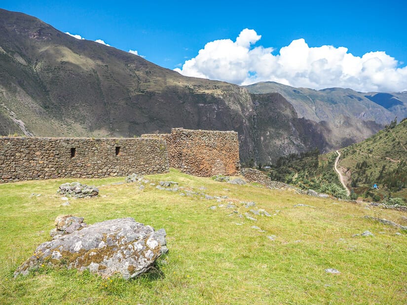 Some ruins and grassy field overlooking a mountainous valley