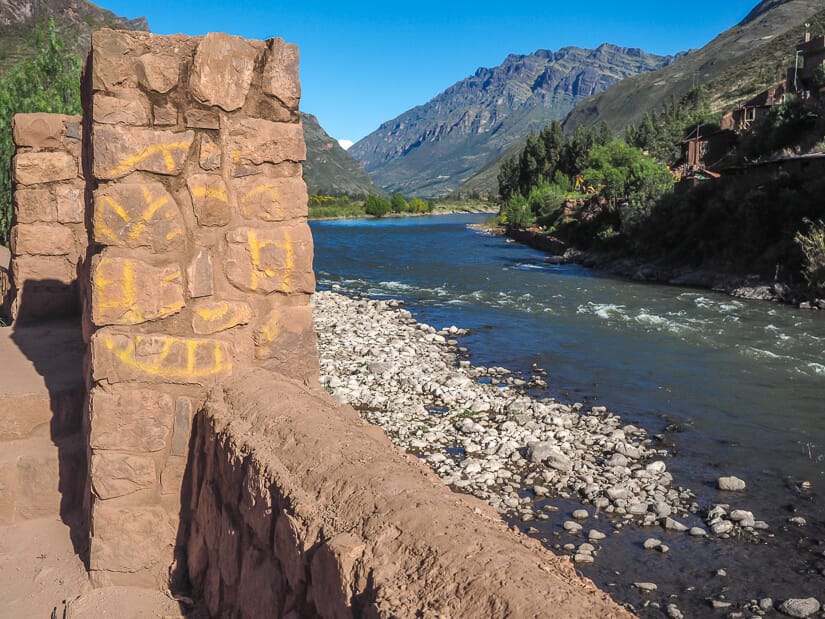 A stone wall beside a pretty river with mountains on other side