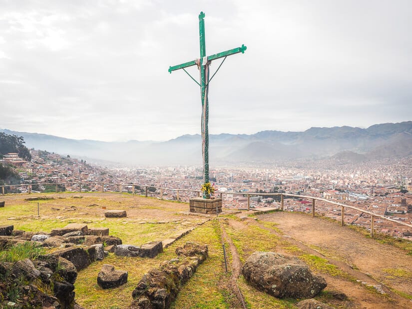 A large cross beside the ruins of Sacsaywaman looking over Cusco
