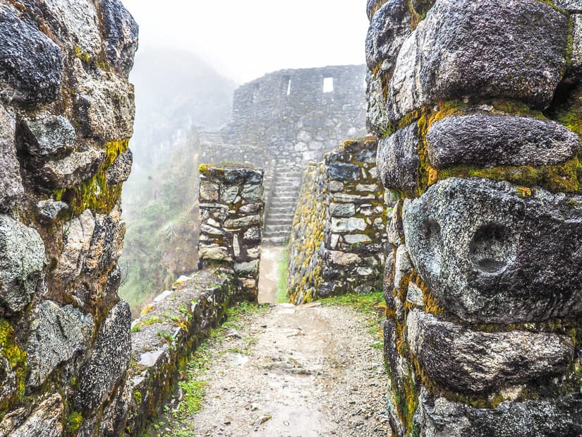 Looking through a stone gate at the ruins of Sayamarca obscured in mist