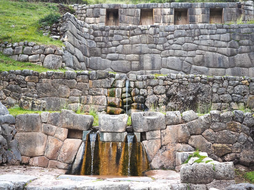 A stone wall with water fountains at Tambomachay ruins close to Cusco