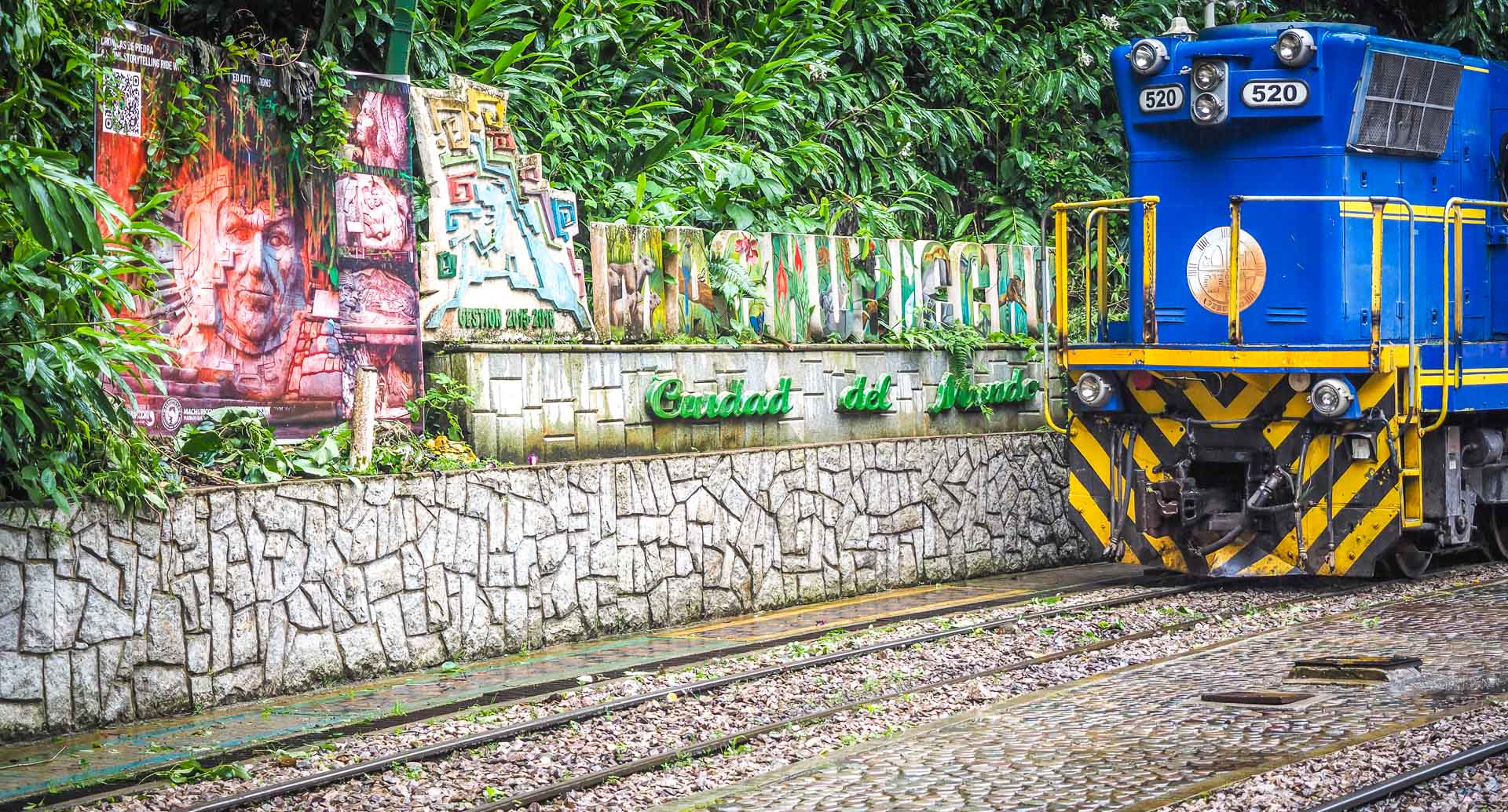 A Machu Picchu sign and blue train parked in Aguas Calientes Peru