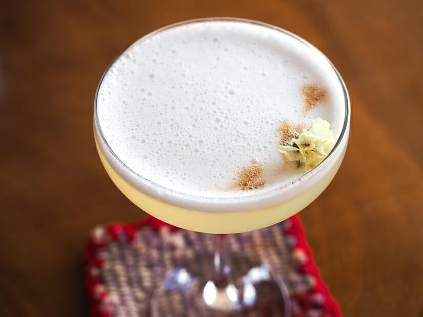 Close up of the top of a pisco sour cocktail with a small flower on it