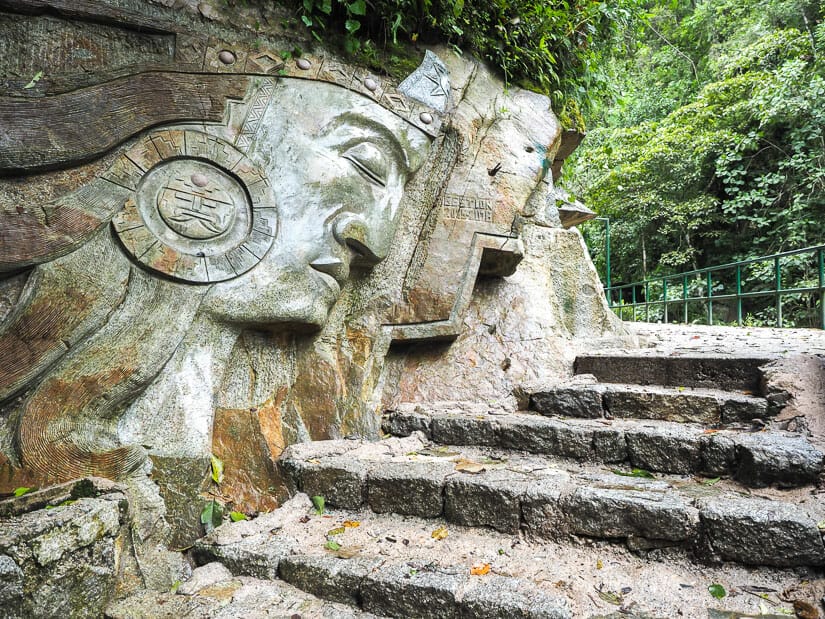 An Inca emperor carved into a rock wall with stone staircase going up beside it