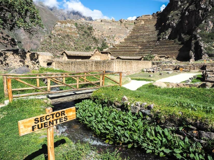 View of the main terraces from the fountain area of Ollantaytambo, with a stream and greenery in the foreground