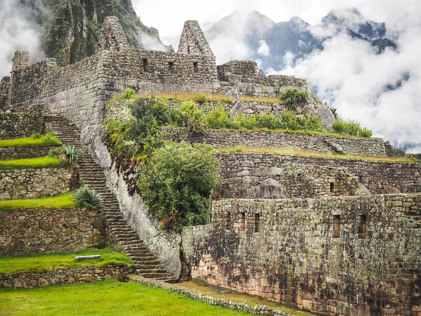 A stone Grand Staircase at Machu Picchu, with ruins, mountains and clouds in background