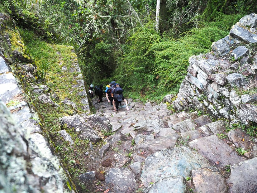 Looking down at a steep stone staircase with a few trekkers climbing up it