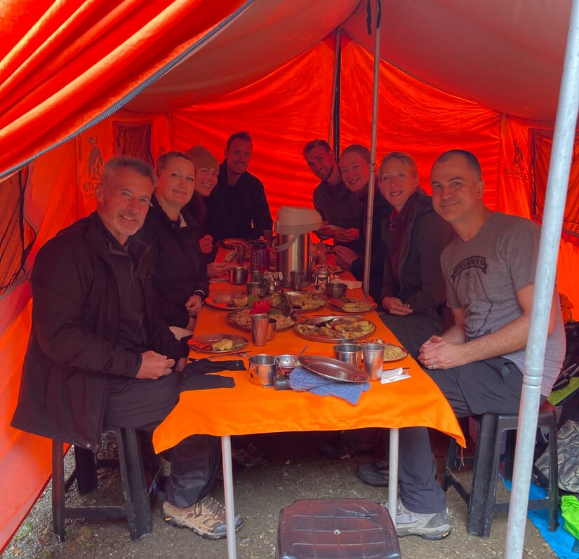 A group of trekkers inside lunch inside an orange tent
