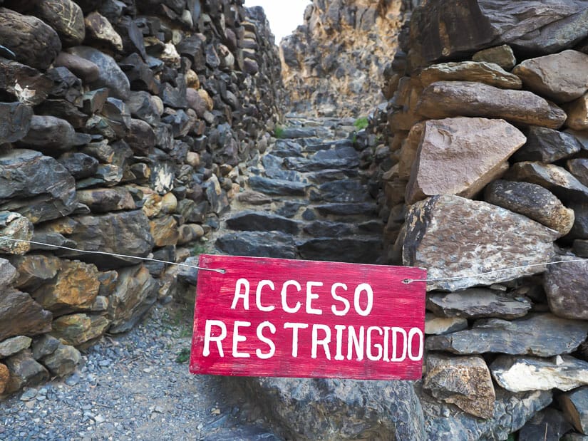 A red sign across a stone path that says "acceso restringido" (access closed)