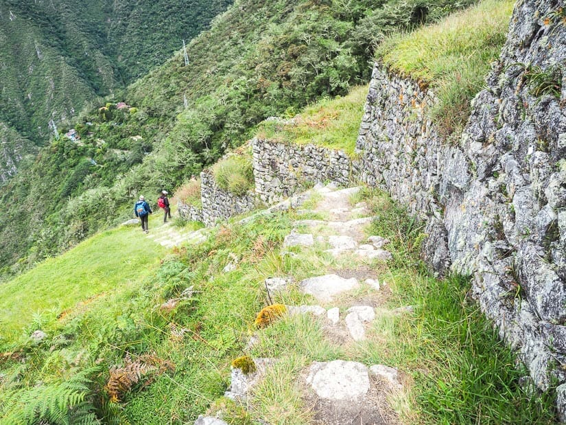 Staircase down from Intipata ruins, with some trekkers going down it, and a campground in background
