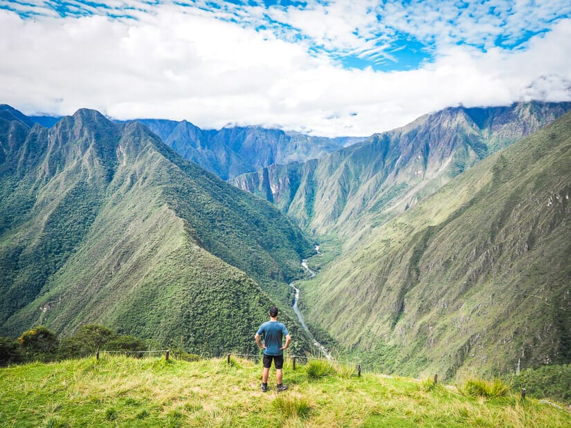 Nick Kembel with his back turned to camera, hands on hips, facing view of a valley from Intipata ruins