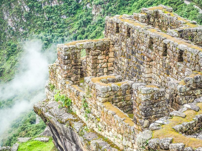 Looking down on some ruins at Machu Picchu with clouds hovering around them