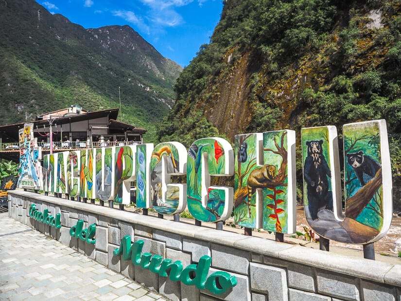 A colorful Machu Picchu sign with mountains and blue sky behind
