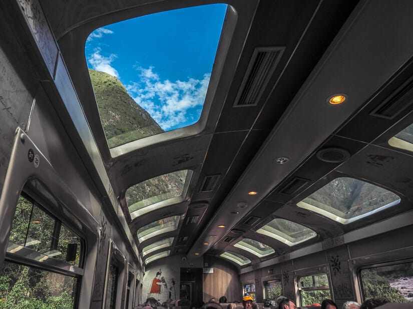 Inside a train with glass roofs and mountains visible outside