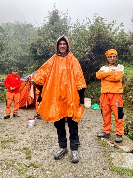Nick Kembel wearing an orange poncho while hiking the Inka trail in the rain