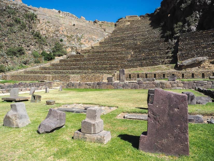 Some stones in a grassy field at the bottom of the Ollantaytambo ruins