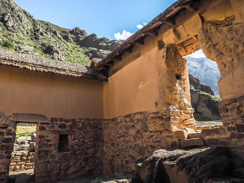 A small stream of water falls off a stone ledge into the interior of the water temple at Ollantaytambo