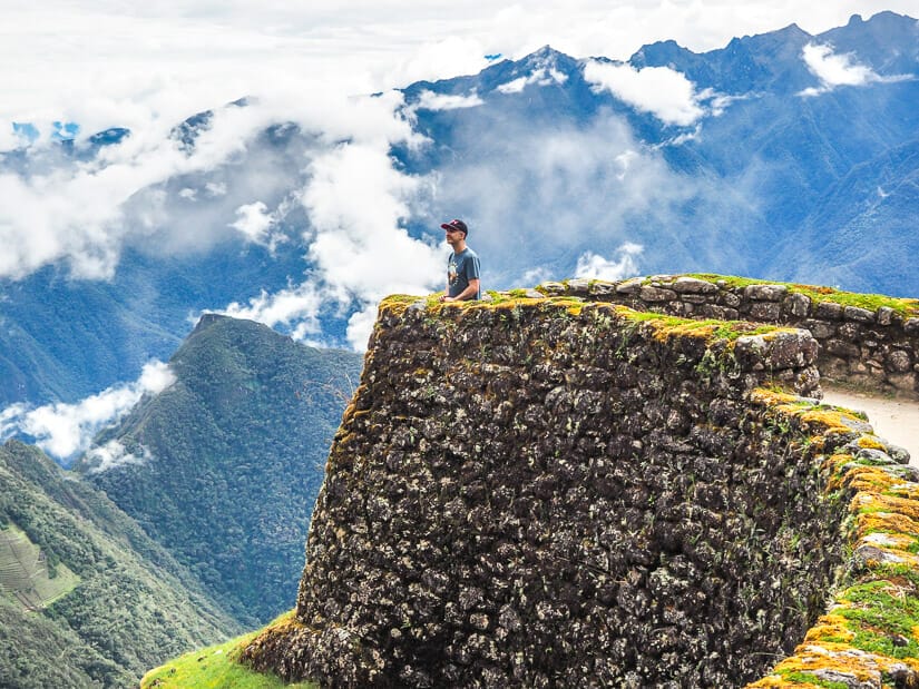 Nick Kembel standing on a platform and Phuyupatamarca ruins and looking at the mountain view