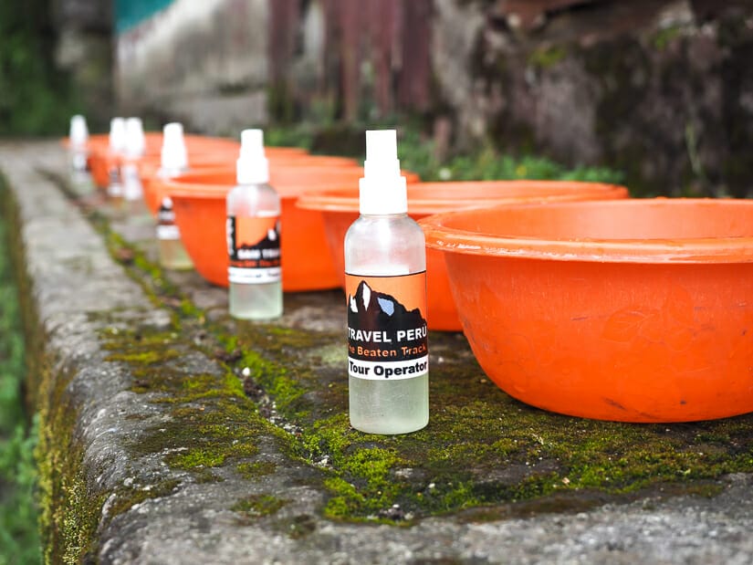 A row of orange wash basins and hand cleaner bottles labeled with Sam Travel Peru logo
