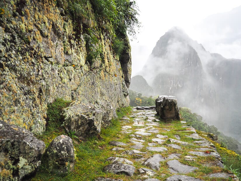 A section of Inca Trail with misty Huayna Picchu mountain in distance