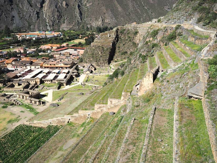 Two sets of green agricultural terraces at Ollantaytambo, with the tourist market and town visible in background