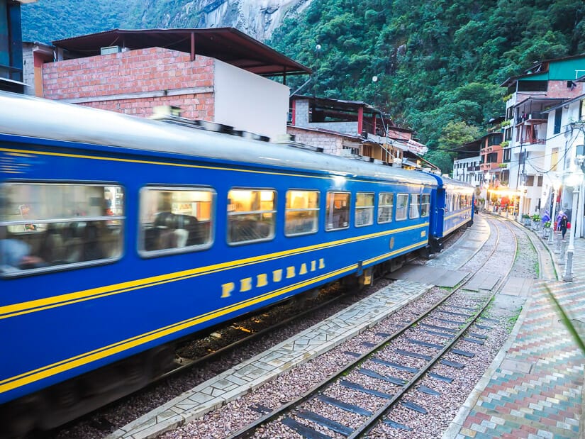 A blue Peru Rail train passing right through Aguas Calientes town
