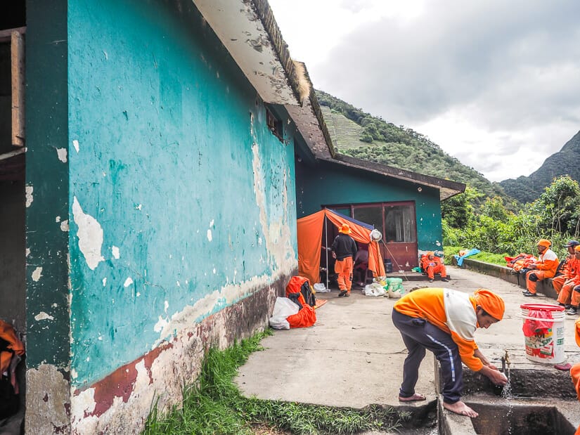A green building at Wiñay Wayna campground that used to be a bar/pub, with some staff of Sam Travel Peru setting up camp beside it