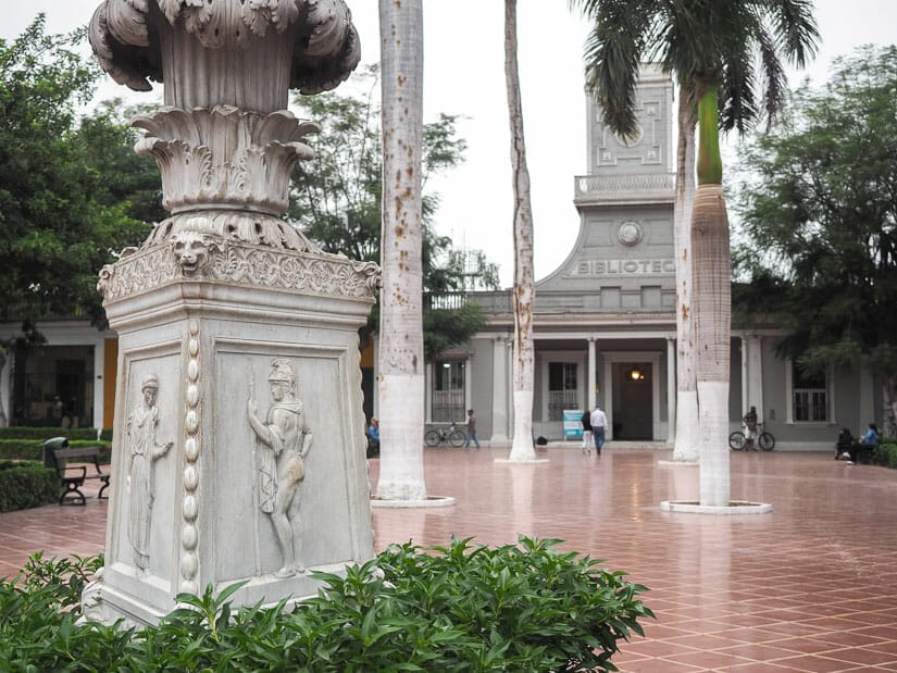 Some monuments and trees in a plaza with tall library building behind