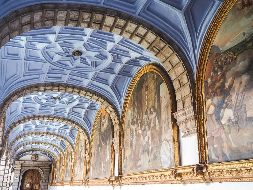 An arched hallways with paintings in each arch