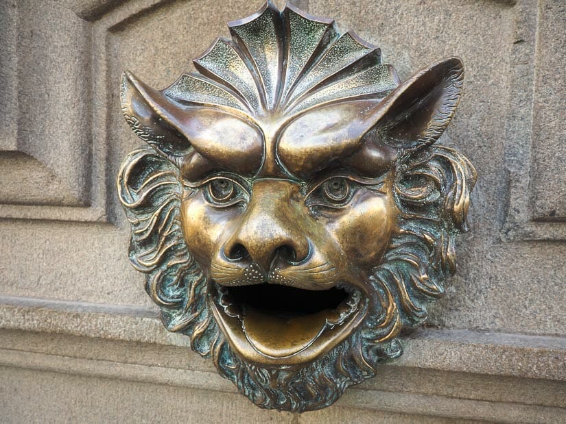 A bronze lion on a wall with its mouth open