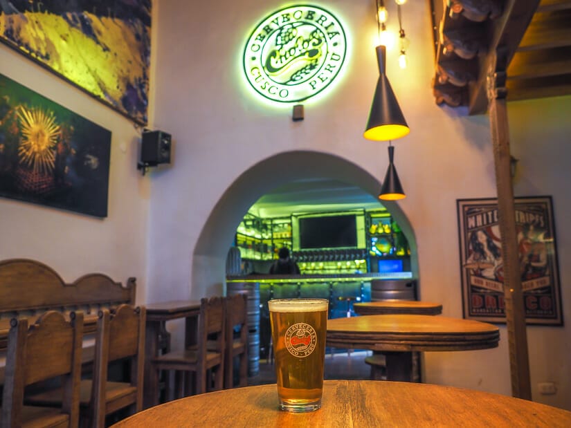 A pint of beer on a table with Cholos Craft Beer Bar sign above