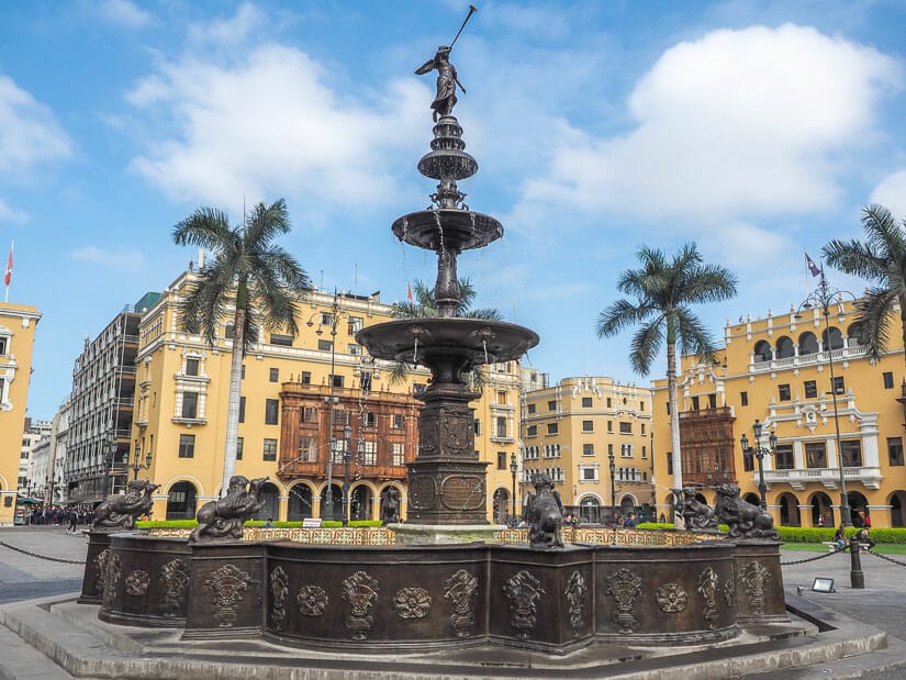 A water fountain with angel blowing trumpet and colonial Lima buildings in background
