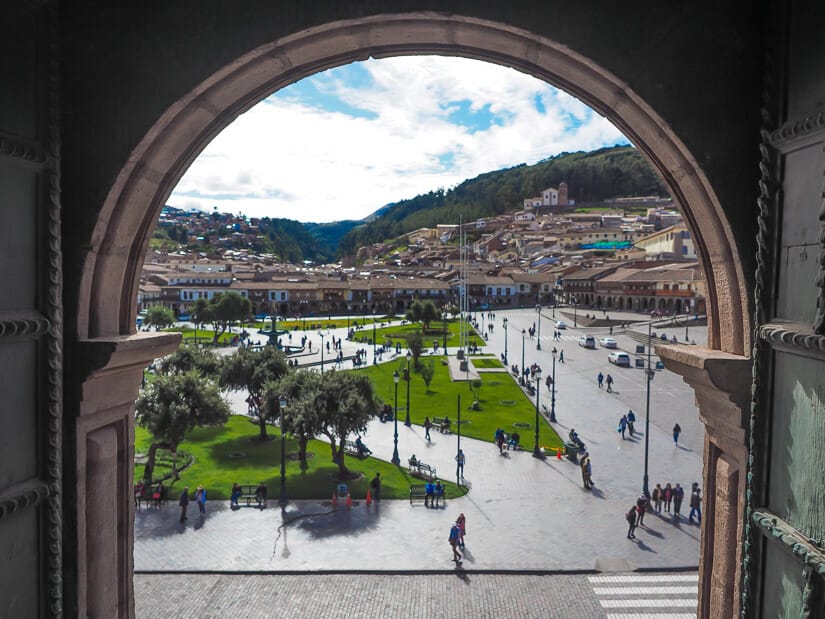 View of Plaza de Armas in Cusco framed by an arched window in the Bell Tower of the Church of Jesus