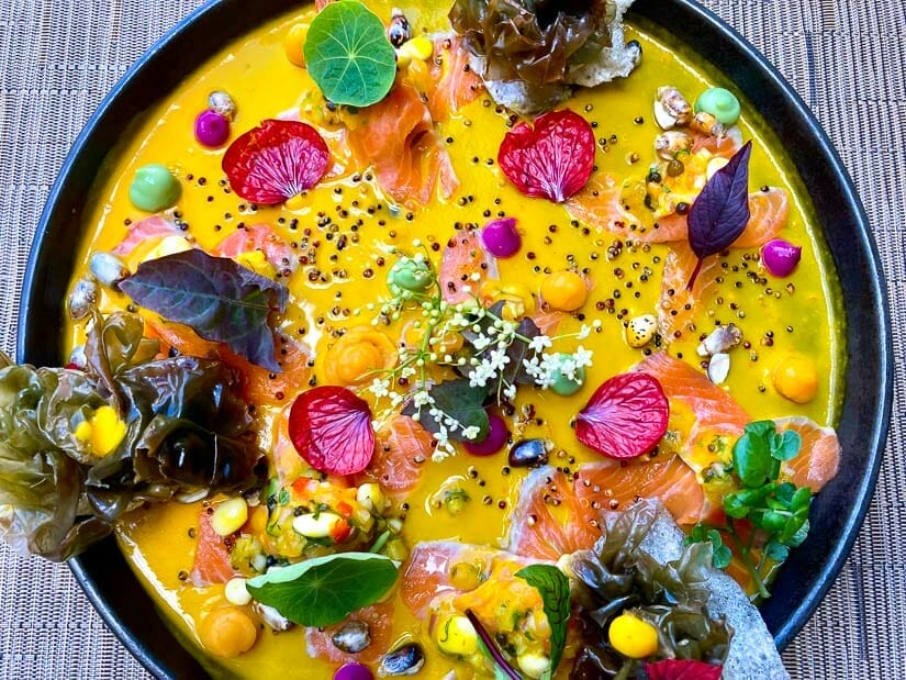 A round plate filled with yellow sauce and various small colorful ingredients