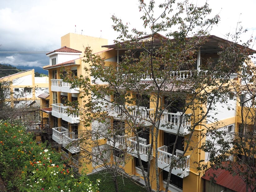 A big yellow old hotel with a few trees block it a little