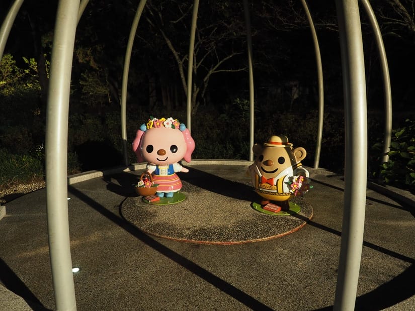 Two 7-11 mascot statues standing inside of a metal tent-shaped cage