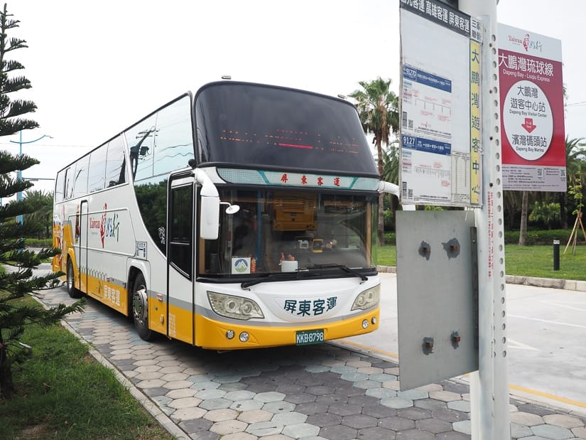 A yellow and white Taiwan Tourism bus parked at a bus stop