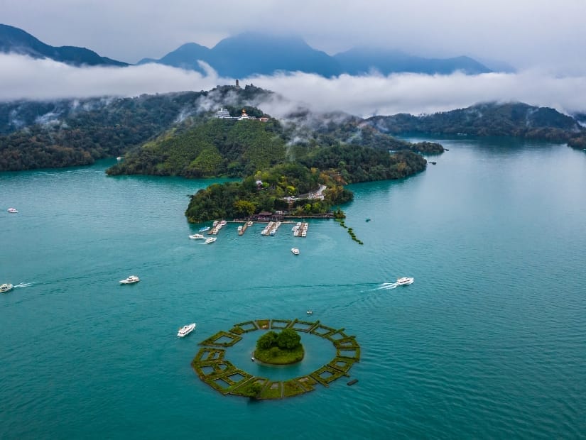 Aerial view of Sun Moon Lake with small Lalu island at the center and some boats on the lake