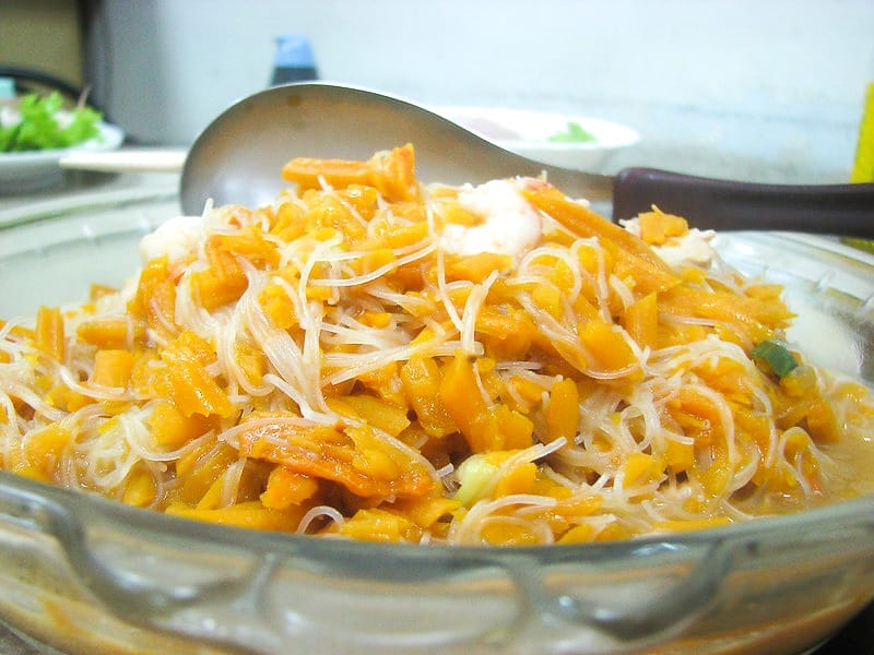 Close up of a large bowl of steamed orange pumkin pieces with vermicelli noodles