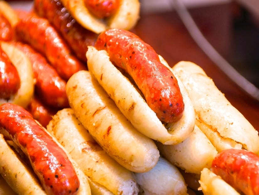 A pile of about a dozen rice sausages, with each one split open and containing a meat sausage