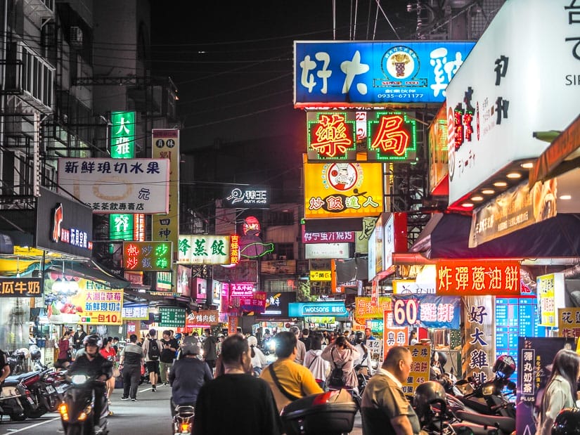 A crowded street in Feng Chia Night Market, with many pedestrians and food stalls