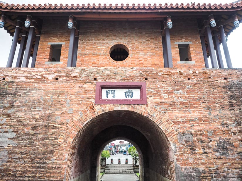 A brick gate structure with arched passageway at the bottom, Chinese characters, and second floor
