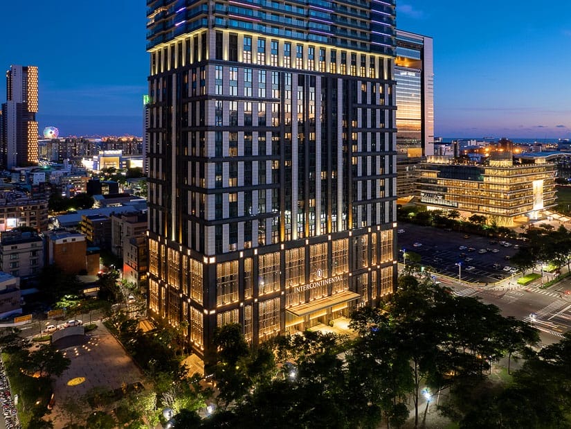 Exterior of the base of a tall building with Intercontinental hotel sign at the bottom, at night