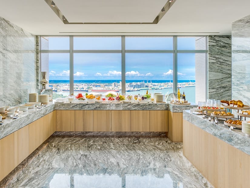 A buffet spread with large window behind with view of Kaohsiung harbor