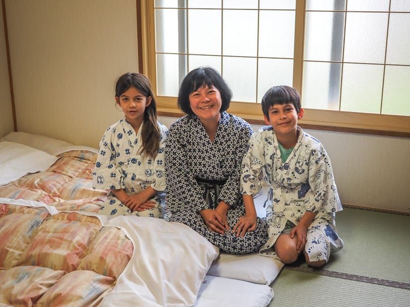 Nick's wife Emily and their two kids wearing Japanese robes, kneeling on the tatami floor beside their beds and smiling for the camera